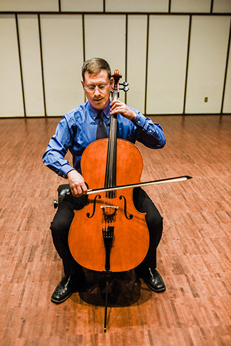 Dr. Benjamin Whitcomb playing cello onstage.